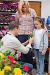 Little girl with her mother getting a present from employee in garden centre