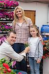 Mother and daugter receving flower pot from garden center employee