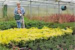 Gardener and gradnchild holding a watering can in greenhouse