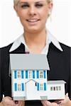 Smiling businesswoman holding a model house against white background