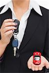 Woman holding key and small car in her palm against white background