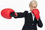 Blonde businesswoman with red gloves boxing against white background