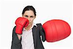 Serious woman wearing red gloves punching against white background