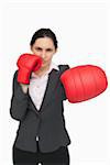 Brunette wearing red gloves punching against white background