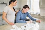 Couple using tablet pc to calculate finances in kitchen