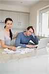 Two people working on finances while using the laptop in the kitchen
