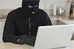 Stranger hacking an unknown laptop and sitting in a kitchen