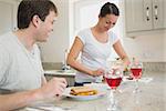 Two young people having lunch and drinking wine in the kitchen