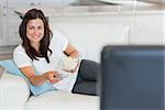 Brunette woman smiling and watching television