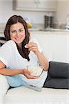 Brunette eating popcorn and relaxing on the sofa