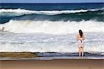 A young woman stands by crashing waves at the beach, St. Lucia Wetlands, Kwa-Zulu Natal, South Africa, Africa