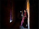 Novice Buddhist monk reading Buddhist scriptures in the light of a window in one of the many temples of Bagan, Myanmar (Burma), Asia