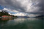 Monsoon clouds gathering over hotel on the edge of the still waters of volcanic Lake Toba, Sumatra