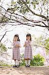 Female twins playing with soap bubbles between cherry trees