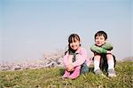 Children sitting on grassland smiling at camera