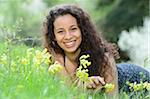 Young woman lying on a meadow beside cowslips in spring, Germany