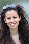 Portrait of a young woman with curly hair wearing sunglasses on head outdoors in spring, Germany