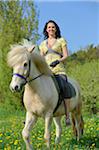 Young woman riding an icelandic horse on a meadow in spring, Germany