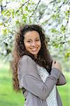 Close-up of a young woman standing beside a flowering cherry tree in spring, Germany