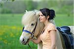 Young woman with a icelandic horse standing on a meadow in spring, Germany