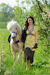 Young woman leading an icelandic horse on a meadow in spring, Germany