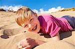 Blonde haired boy lying on beach