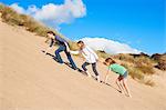 Three girls climbing up sand dune