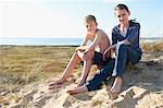 Boy and teenage girl sitting on beach