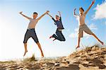 Boys and teenage girl jumping on beach