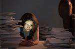 Girl lying on front using cell smartphone surrounded by books