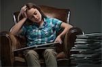 Girl sitting in leather armchair with piles of books