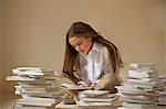 Girl sitting on floor reading surrounded by piles of books