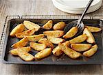 Seasoned potato wedges. Seasoned with salt and pepper on baking tray and wire rack