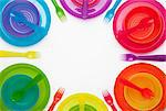 Colourful plastic plates, cups, bowls, spoons and forks