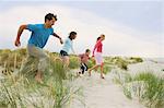 Family holding hands and running at the beach