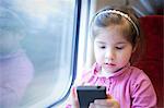 Little girl on train, playing game on smartphone