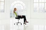 Businesswoman sitting on office chair in sparse white room