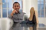 Male office worker sitting at desk with feet up