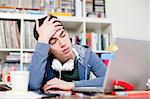 Worried male student with hand in hair using laptop