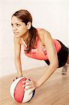 Young woman doing press ups on basketball