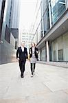 Businessman and businesswoman walking past office buildings