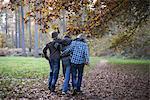 Boys walking through forest with arms around eachother