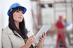 Portrait of woman with blue hard hat and digital tablet