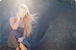 Young woman with long blonde hair sitting on rocks