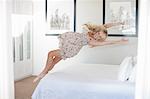 Young woman jumping on bed