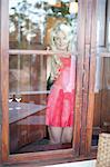 Young woman wearing red dress looking through glass door