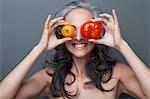 Mature woman covering eyes with red and yellow tomato