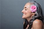 Mature woman with pink flower in hair, eyes closed