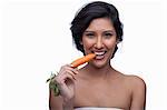 Young woman biting carrot