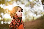 Portrait of male toddler in tiger suit alone in woods